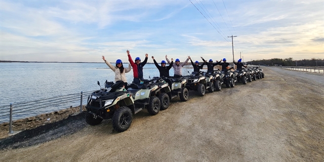 People riding ATVs by a lake.