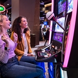 Women playing a slot machine.