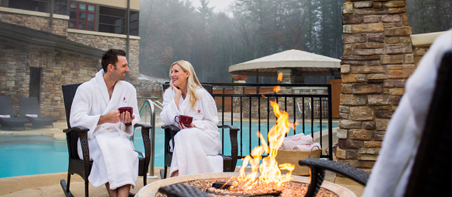 Couple enjoying a warm drink by a fire pit