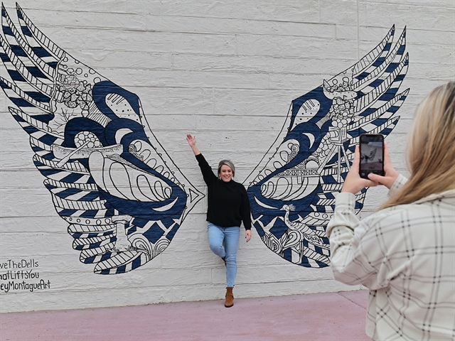 Women taking a picture at the wings mural at Elm Street Plaza.