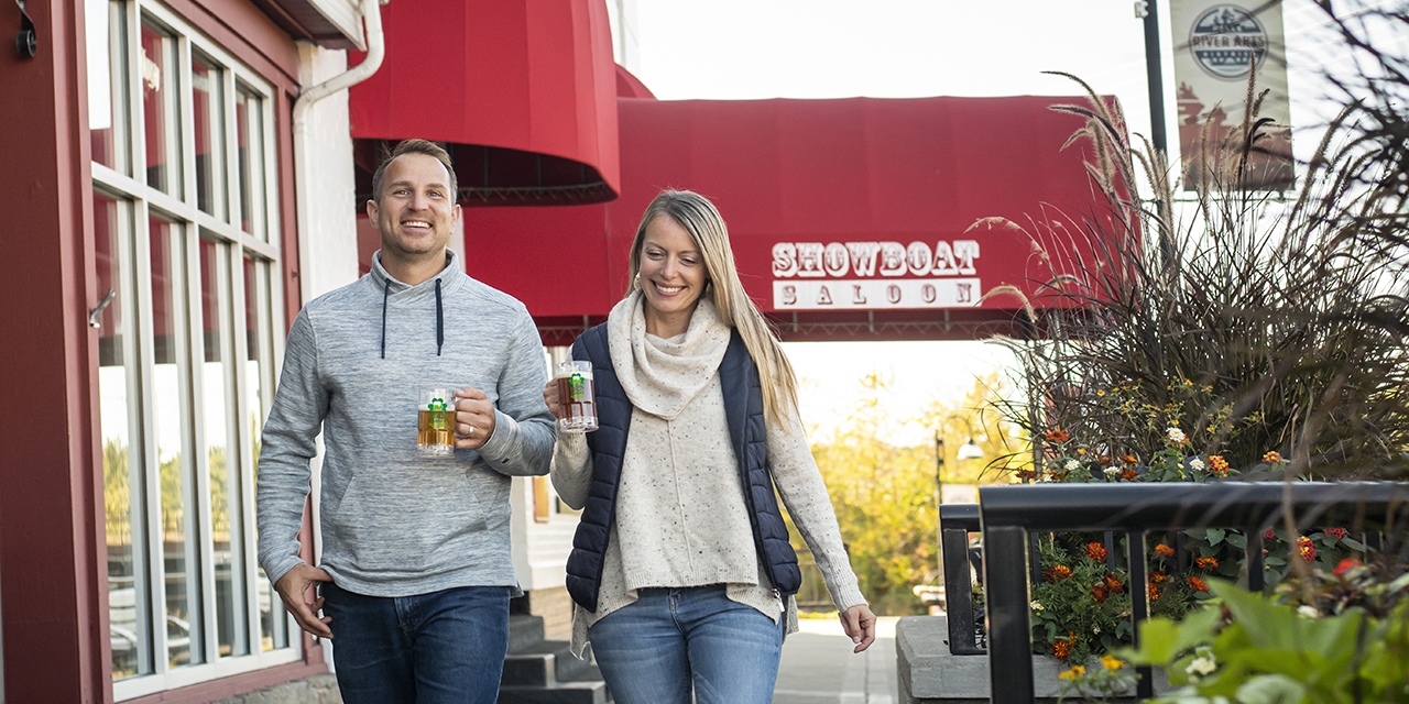 Couple walking in Downtown Dells holding a cup.