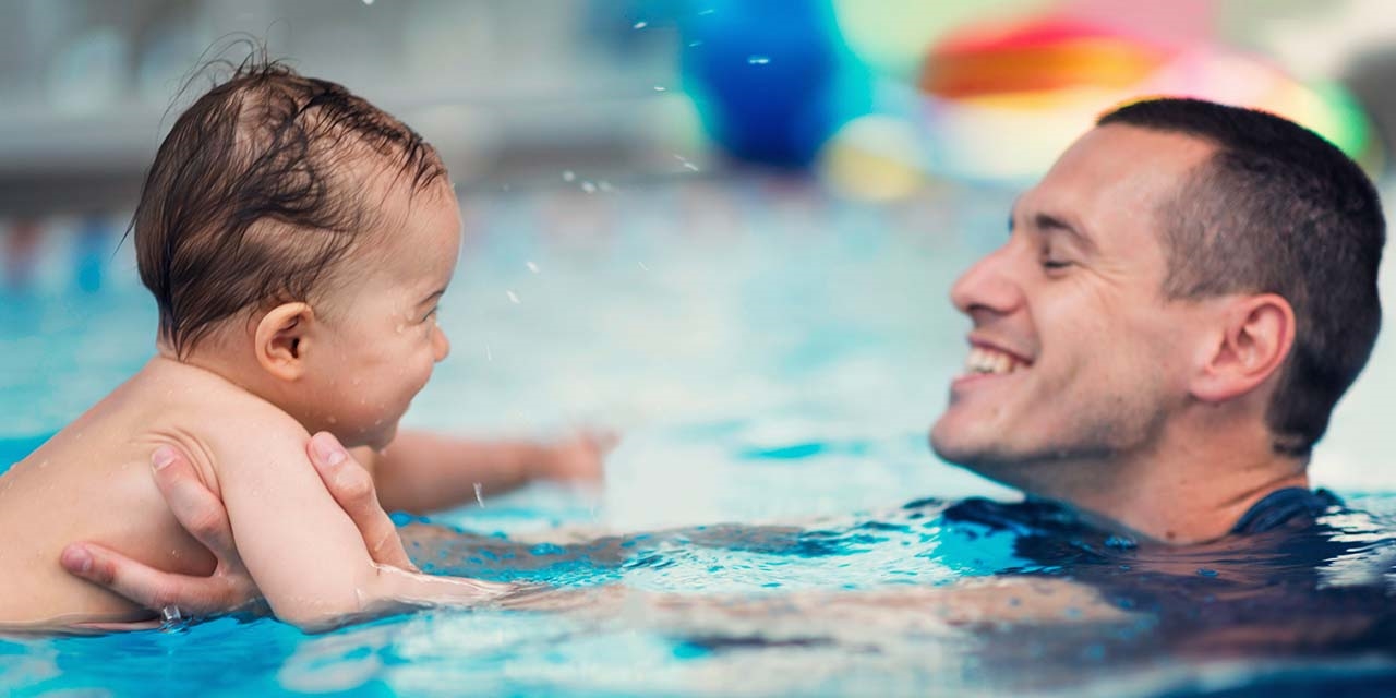 Father and toddler swimming in a pool