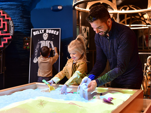 kid and dad playing at sand table