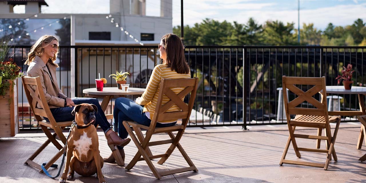 Two women sitting at Riverfront Terrace with a dog