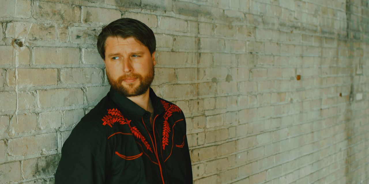 Derek James leaning up against a wall