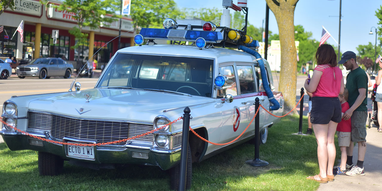 A family looking at a replica ECTO-1 from Ghostbusters at Hollywood at Elm Street Plaza.