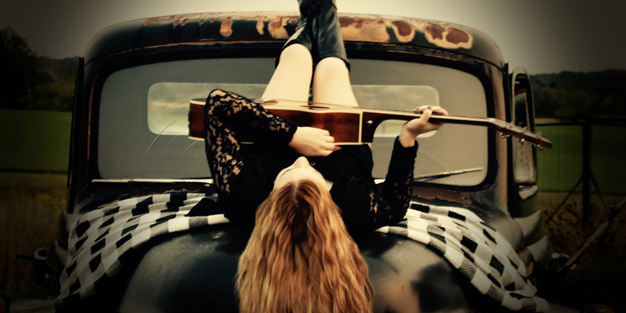 Annie Marie paying guitar on hood of truck