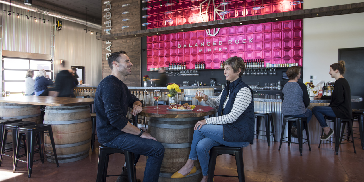 Two people sit at a table enjoying food and drinks.
