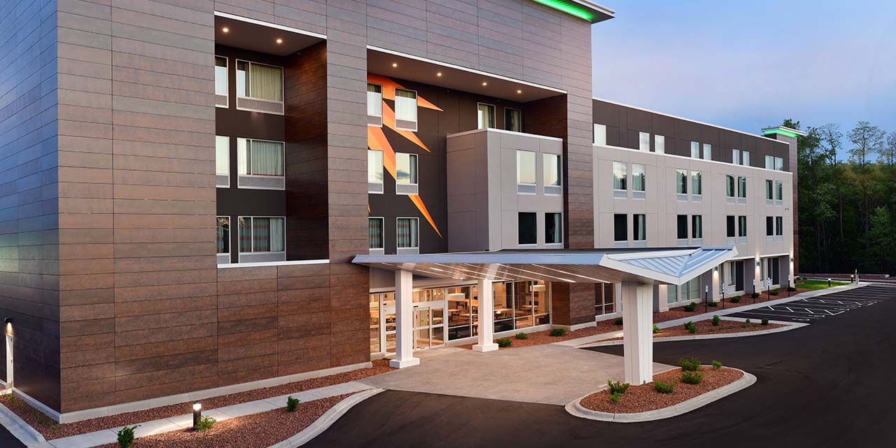 A grey hotel building stands in front of scenic woods in Wisconsin Dells