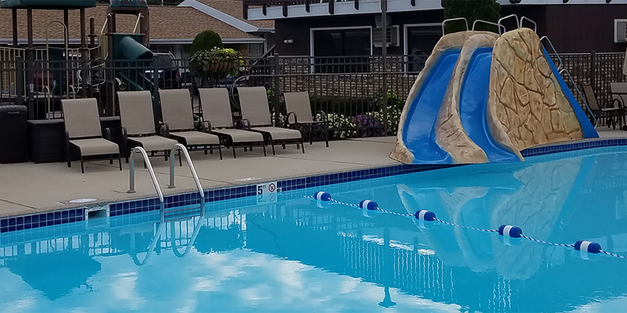 Outdoor pool with slide and poolside seats.