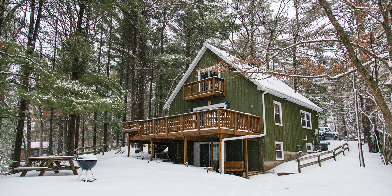A green vacation rental home with a dusting of snow.
