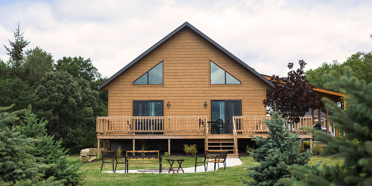 Cabin home exterior with fireplace and benches.