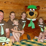 A family gets a picture with Yogi Bear inside a resort room.