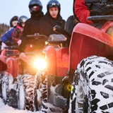 Family riding ATVs in snow.
