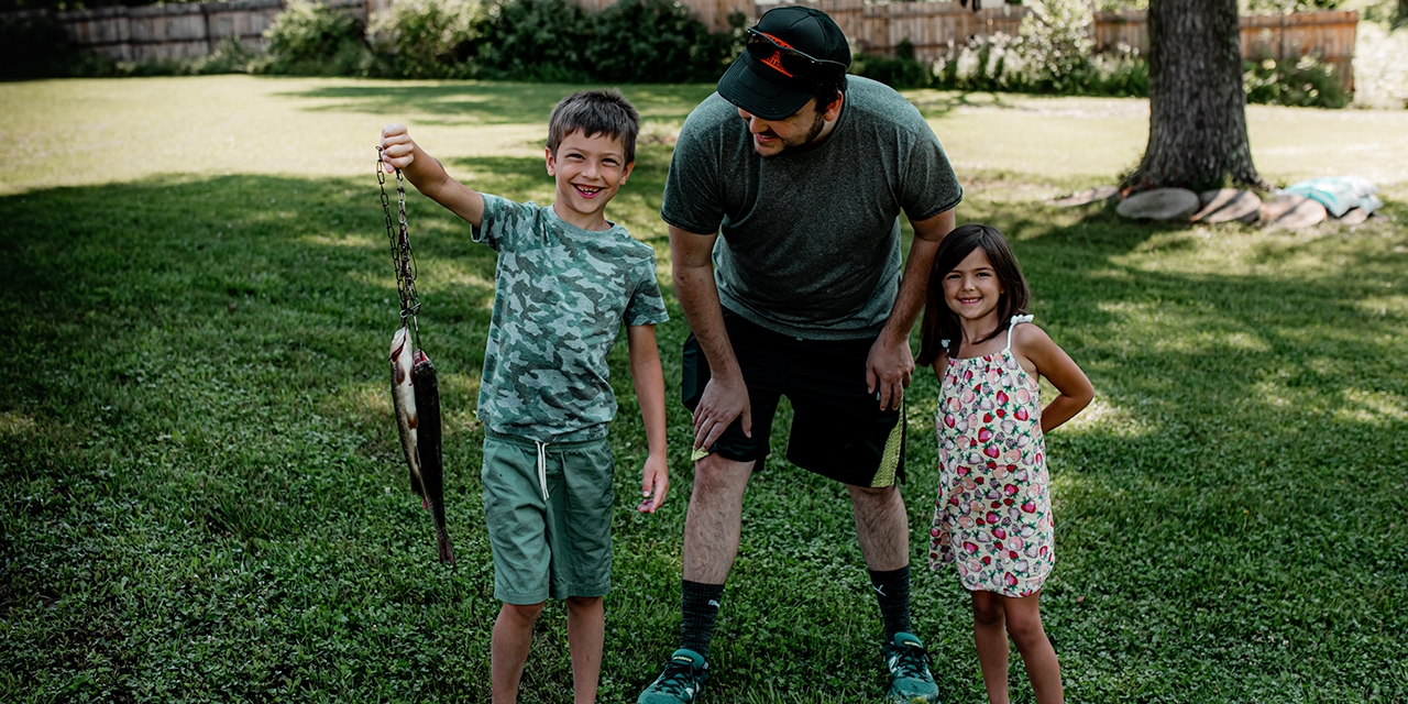 A boy shows off the fish he caught.
