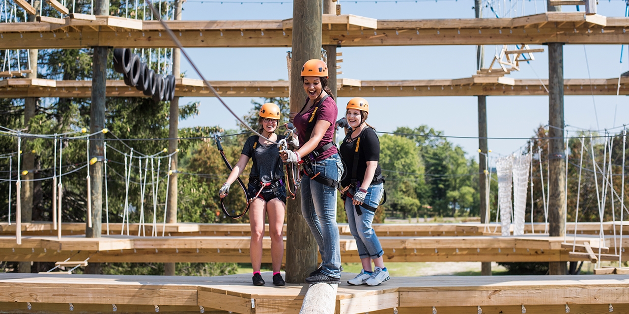 People cross a log on the ropes course at BigFoot Ropes Course.