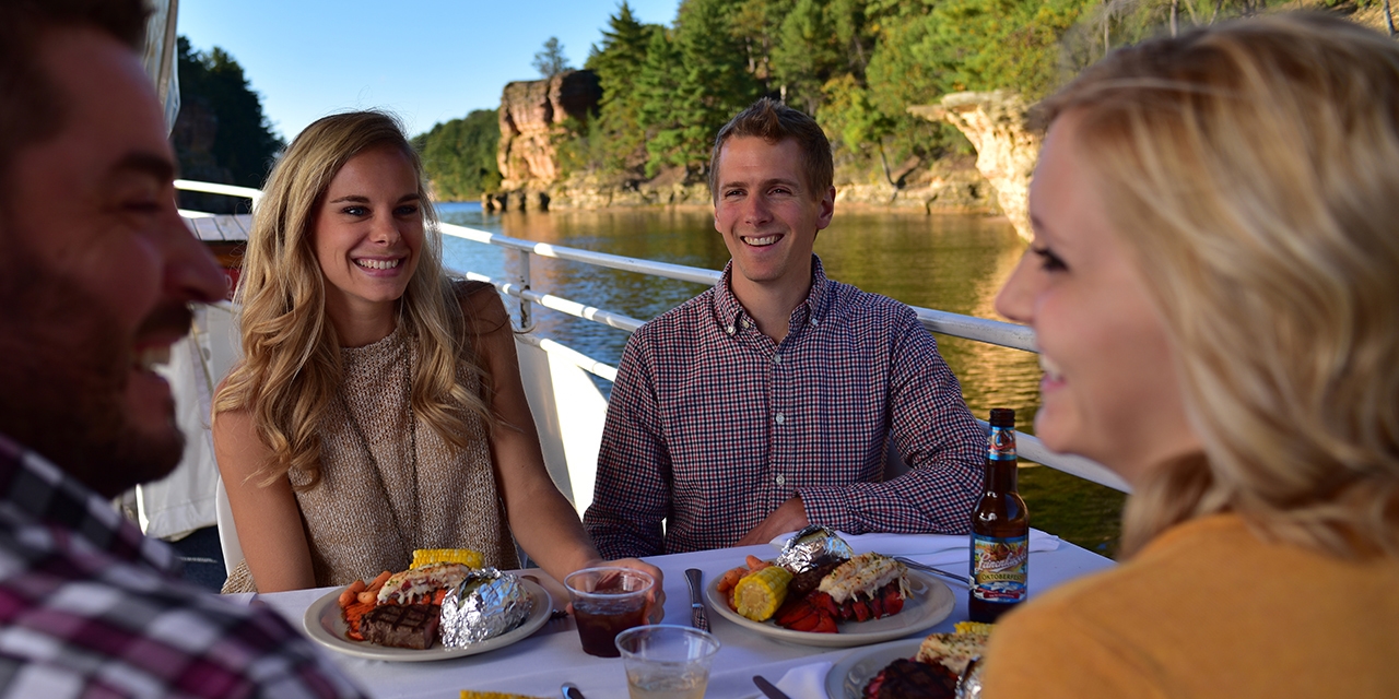 Guests dine as the sun sets aboard a dinner cruise.
