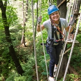 A girl makes her way across high ropes in the woods.