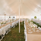 Outdoor event setting with chairs, tables, and centerpieces.