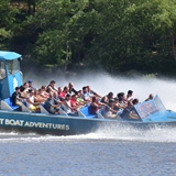 Visitors as sprayed by water as a jet boat splashes water.