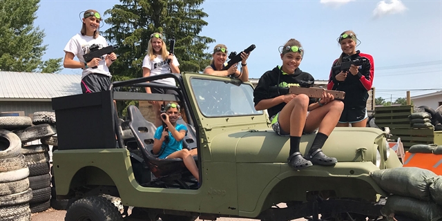Kids pose on a Jeep with laser tag gear.