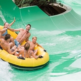 A family goes down a waterslide together.