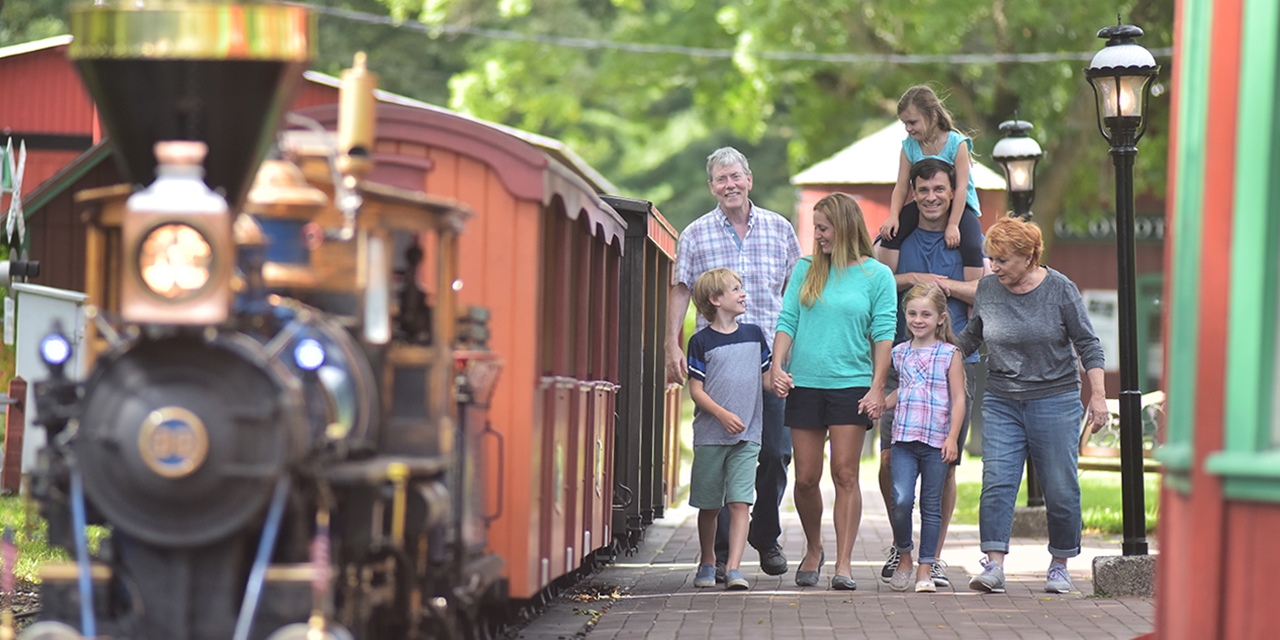 A family walks alongside a train at Riverside & Great Northern Railway