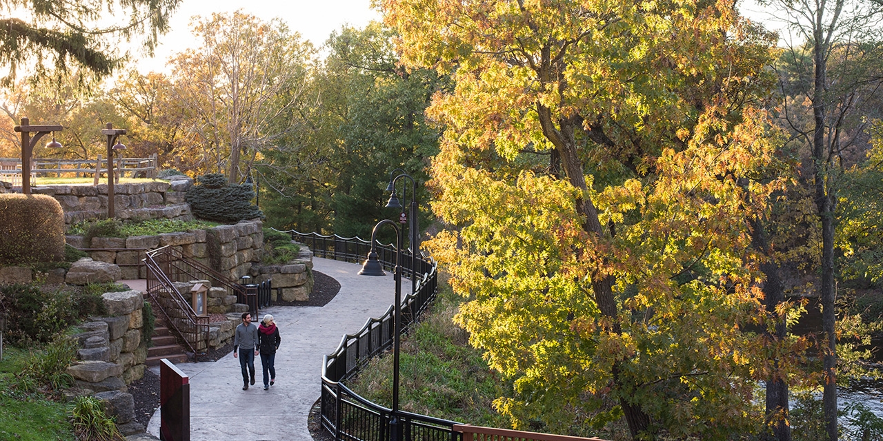 A couple walks along the Scenic River Walk admiring the fall foliage.