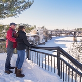 A couple stands on the Scenic River Walk in winter.