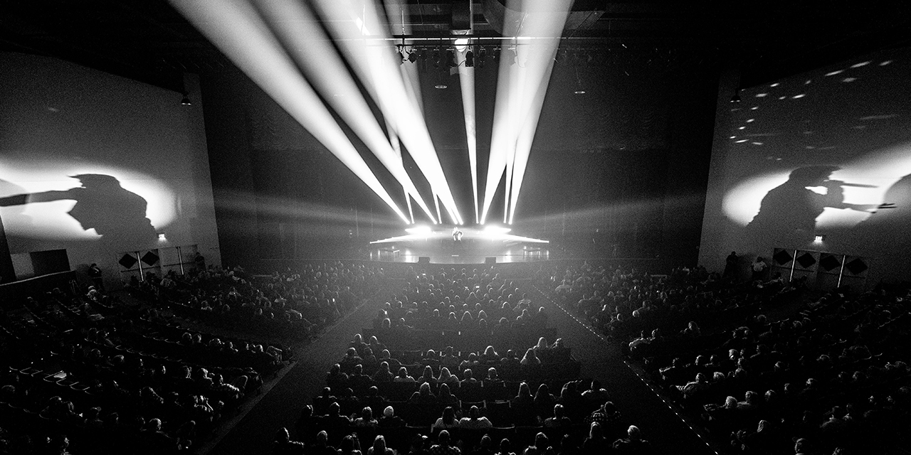 Black and white image of Crystal Grand venue audience and artist on a stage.