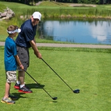A father and son practice their driver swing.