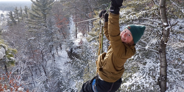 A woman ziplines in the snow-dusted landscape.