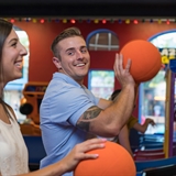 Couple playing basketball at an arcade.