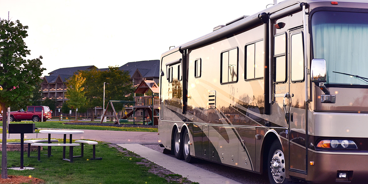 An RV parked with a picnic table, fire pit, and green space.