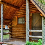 Log cabin exterior with front porch and picnic table.