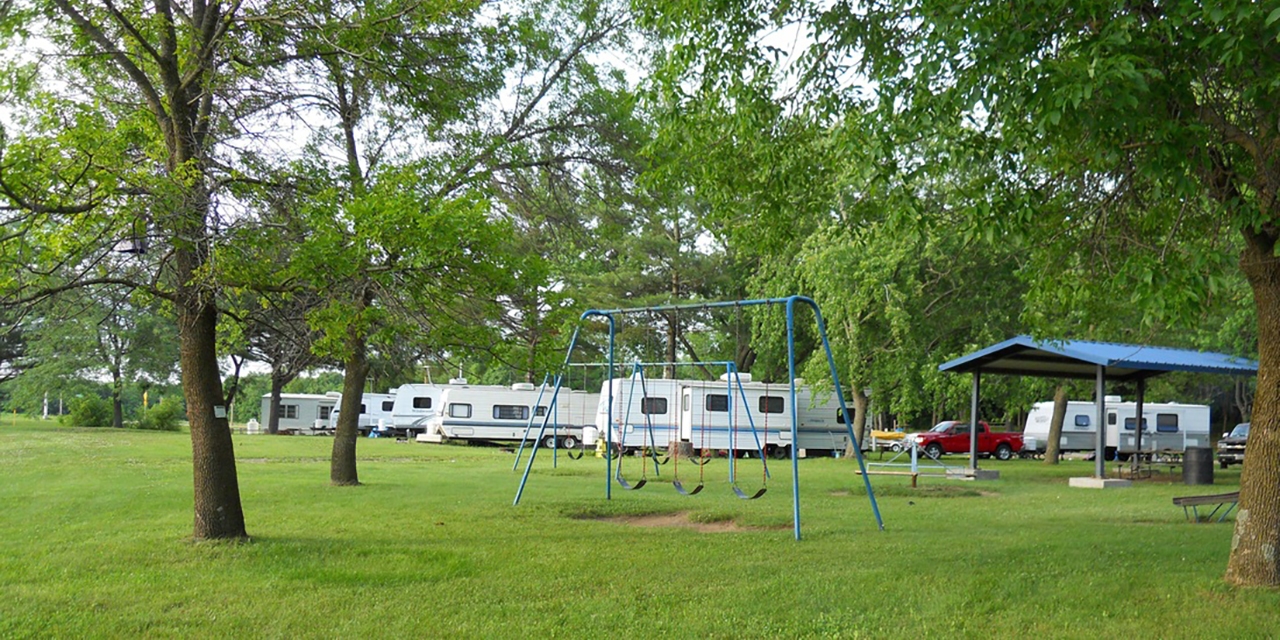 Campers, a pavilion, and a park with a swing set at Red Oak Campground.