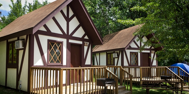 Tudor style lodging with a front porch and nearby camping area and woods.