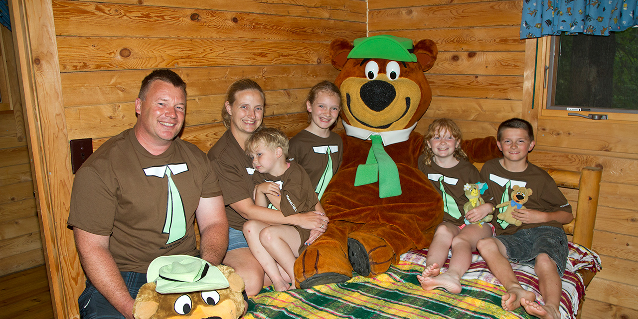 A family gets a picture with Yogi Bear at their cabin lodging.