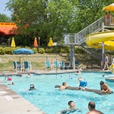 People enjoy the outdoor pool with slide and basketball hoops.