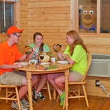 People socialize in a cabin as Yogi Bear looks in.