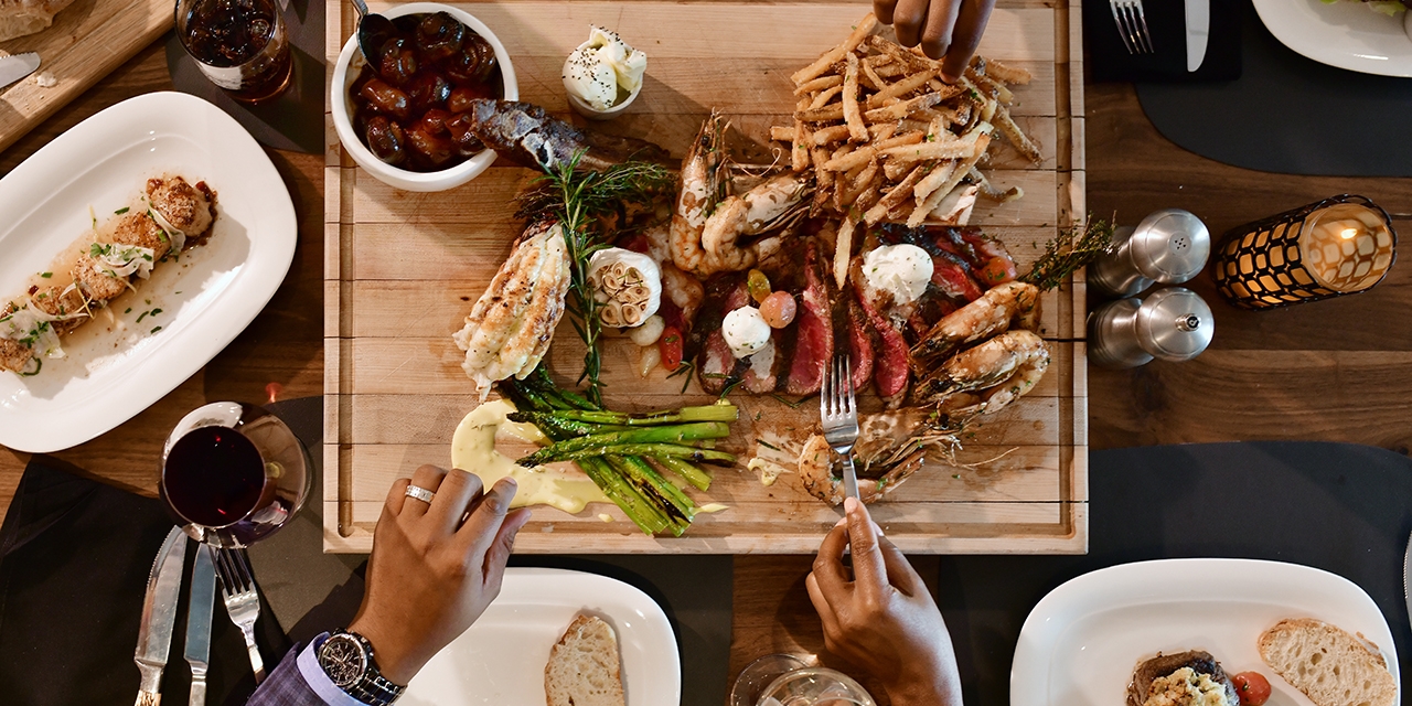 A group of people share steak, lobster, shrimp, and more.