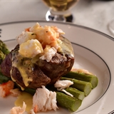 A steak topped with crab sitting on a bed of asparagus.
