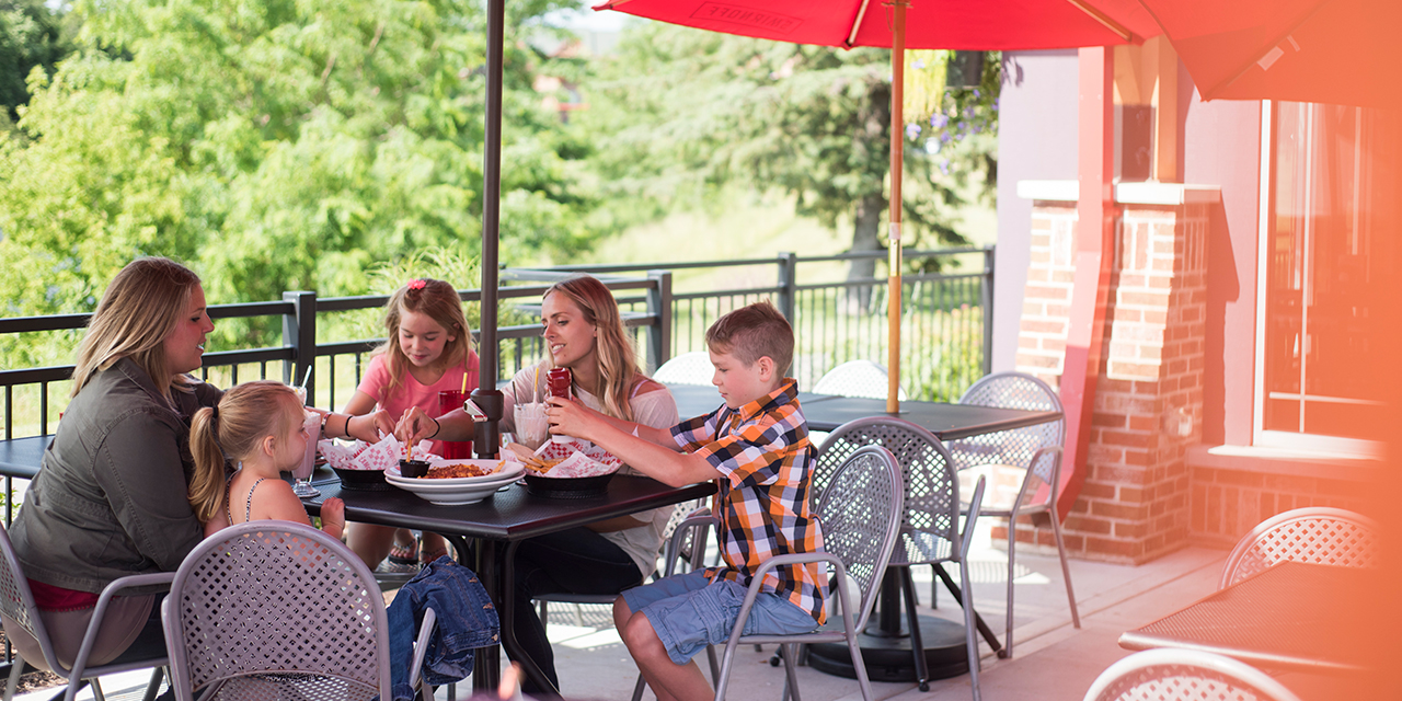 People dining outdoors at Monk's Bar & Grill at the Wilderness.