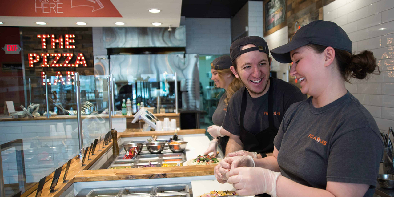 Workers making a pizza at Dells Pizza Lab.