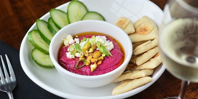A roasted beet hummus bowl with pita and cucumbers.