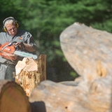 A man carves wood with a chainsaw.